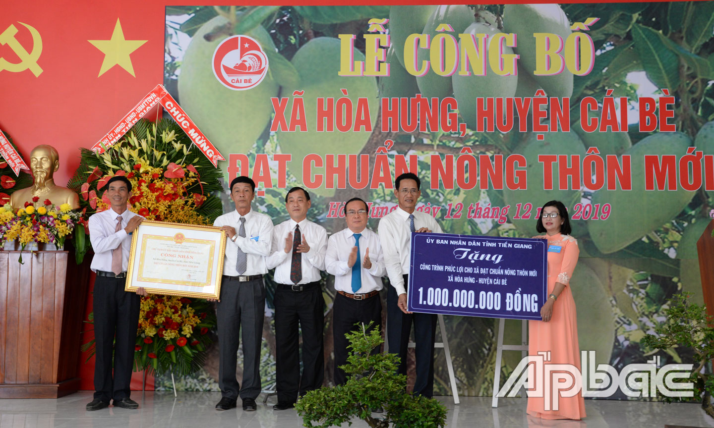 Đồng chí Nguyễn Văn Vĩnh và đồng chí Phạm Anh Tuấn trao Bằng công nhận xã đạt chuẩn NTM và Bảng tượng trưng tặng công trình phúc lợi 1 tỷ đồng cho xã Hòa Hưng.