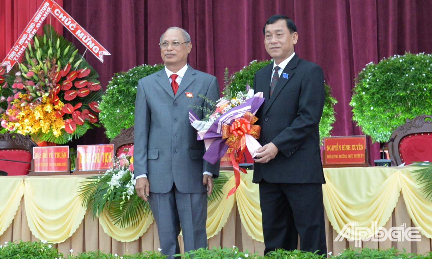 Đồng chí Đỗ Vũ Thuận (bìa trái), Bí thư Huyện ủy Tân Phước tặng hoa đồng chí Nguyễn Văn Vĩnh.