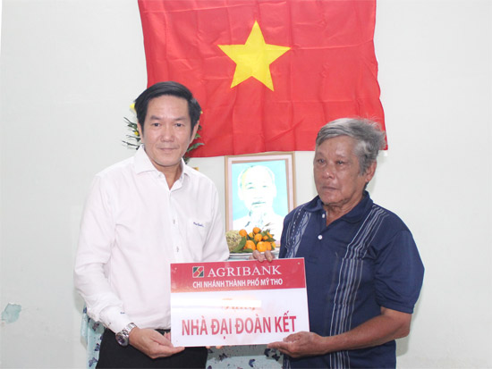 Ông Trường Văn Đoàn, Chủ tịch Công đoàn cơ sở Agribank Tiền Giang trao biển tượng trưng bàn giao nhà cho ông Lê Văn Tiết