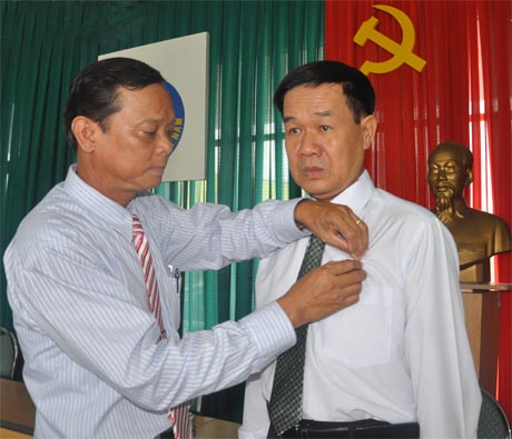 Bí thư Đảng ủy NguyễThanh Nhàn gắn Huy hiệu 30 nămtuổi Đảng cho Nhà báo Mạnh Tiến.