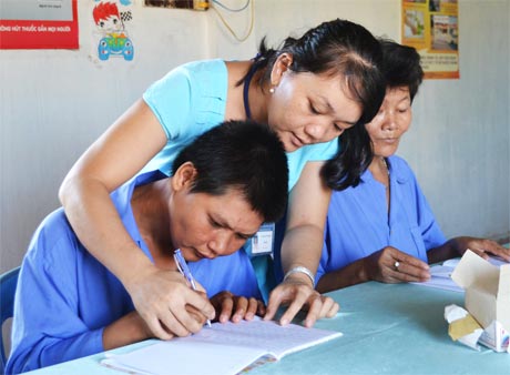 Chị Lê Thị Tuyết Thanh cặm cụi cầm tay đối tượng để giúp họ nắn nót viết từng con chữ.