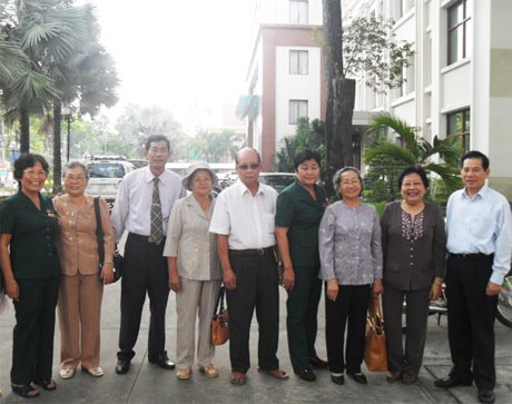 Chủ tịch nước Nguyễn Minh Triết (bìa phải) chụp ảnh với đồng đội TNXP Tiền Giang (chị Kim Anh bìa trái). 				     Ảnh: ĐẬU VIẾT HƯƠNG