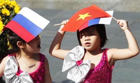 Các em bé mang Quốc kỳ Việt Nam và Nga chờ đón Tổng thống Putin tại Hà Nội. Ảnh: AFP