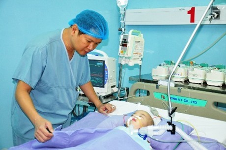 TS.BS Trương Quang Định, người tổng chỉ huy ca phẫu thuật, bên bé Phi Long sau khi được tách rời. Ảnh: VGP