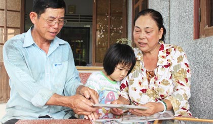 Cô chú cùng đứa cháu ngoại đang xem hình ảnh gia đình.