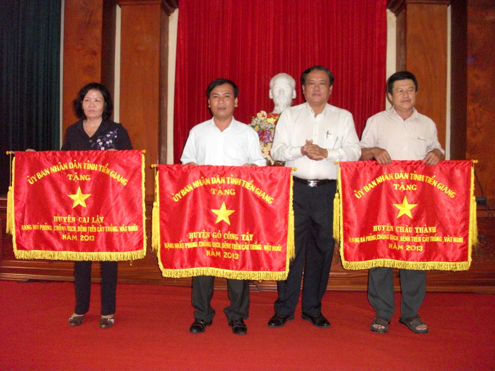 Ông Lê Văn Nghĩa, Phó Chủ tịch UBND tỉnh trao Cờ thi đua hạng nhì, hạng nhất và hạng ba của UBND tỉnh cho Nhân dân và cán bộ huyện Cai Lậy, Gò Công Tây và Châu Thành (từ trái sang).