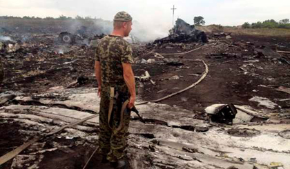 Một dân quân Ukraine ly khai đứng bên hiện trường chiếc máy bay Boeing 777 xấu số của của Malaysia Airlines ngày 17-7. (Ảnh: Reuters)
