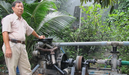 Ông Lê Phước Lộc và hệ thống tưới sử dụng péc phun vừa được ông cải tiến ở bộ phận truyền động.