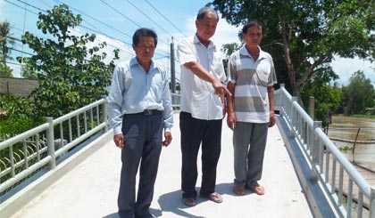 Ông Võ Văn Dũng (đứng giữa) tích cực đóng góp kinh phí  và vận động người dân  xây dựng cơ sở hạ tầng nơi cư trú. 