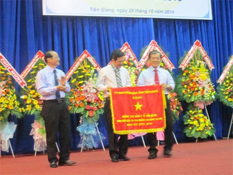 Ông Trần Thanh Đức, Phó Chủ tịch UBND tỉnh trao Cờ thi đua hạng Nhất cho lãnh đạo Trường CĐYT Tiền Giang.