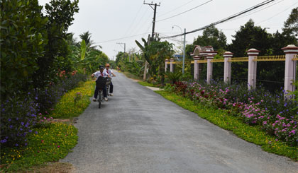 Sau 4 năm xây dựng NTM, cảnh quan, môi trường nông thôn ở xã Ngũ Hiệp, huyện Cai Lậy ngày càng khởi sắc. (Trong ảnh: Các em học sinh xã Ngũ Hiệp nô nức đến trường trên con đường rợp bóng cây xanh và hoa).     Ảnh : NGỌC LAN