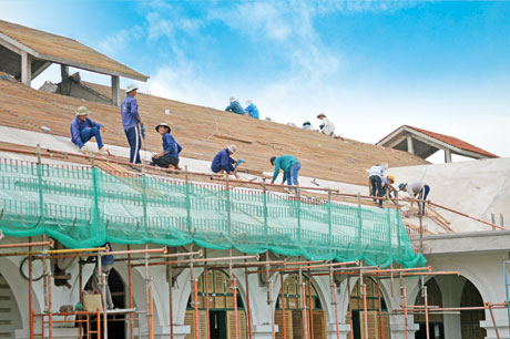 Không khó để bắt gặp cảnh công nhân xây dựng làm việc trong điều kiện hết sức nguy hiểm để hoàn thành công trình  (Ảnh chụp tại nóc nhà tầng 4 công trình Trường THPT Nguyễn Đình Chiểu, TP. Mỹ Tho).