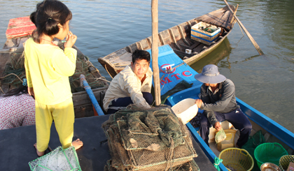 Anh Phạm Văn Dũng đang cân tôm, cá cho thương lái.