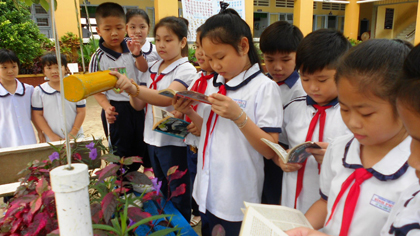  Học sinh đọc sách tại “Thư viện xanh” Trường Tiểu học Bình Phú.