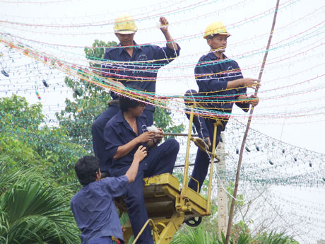 Dù mồ hôi ướt đẫm trên lưng áo nhưng các công nhân vẫn vui khi tham gia lắp đặt mạng lưới điện chiếu sáng đường phố.