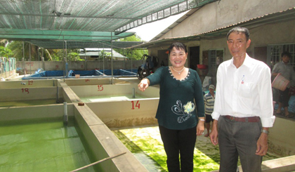 	Chị Nguyễn Thị Nghiệm đang giới thiệu với ông Huỳnh Văn Phước các ao ương cá bột thành cá giống.