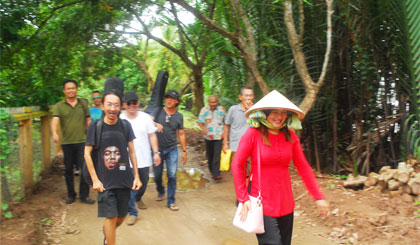 Hướng dẫn viên (bên phải) hướng dẫn khách du lịch tại khu du lịch Thới Sơn.