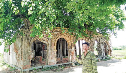 Anh Lê Tấn Thông đang lo hương khói cho đình Tân Đông, chỉ tay giới thiệu nét đẹp của 2 bộ rễ bồ đề ôm lấy 5 vòm cửa.