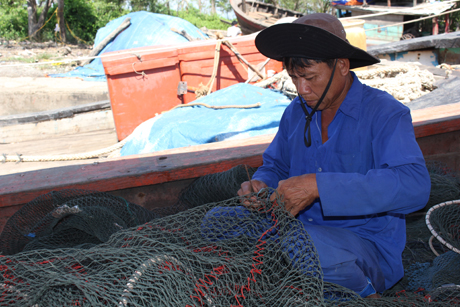 Chú Tám (xã Tân Điền, huyện Gò Công Đông) vá lại miệng lưới cào ốc mỡ và chờ thời tiết thuận lợi để ra khơi.