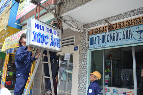 Tháo dỡ một bảng hiệu vi phạm của người dân.
