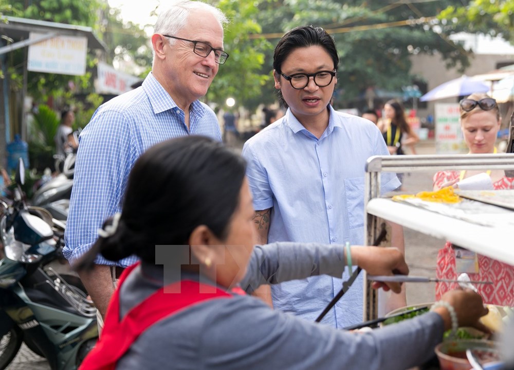 Thủ tướng Australia Malcolm Turnbull cùng đầu bếp người Australia gốc Việt Luke Nguyen ăn sáng với món bánh mỳ tại một cửa hàng ở thành phố Đà Nẵng. (Nguồn: TTXVN)