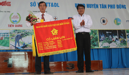 Phó Chủ tịch UBND huyện Tân Phú Đông Nguyễn Văn Dũng trao cờ luân lưu cho đại diện UBND huyện Gò Công Tây, đơn vị sẽ đăng cai Giải Việt dã Báo Ấp Bắc lần thứ 36 - năm 2019.