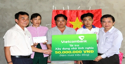 Ông Trần Phúc Cường (bìa phải) trao bảng tượng trưng cho gia đình anh Được