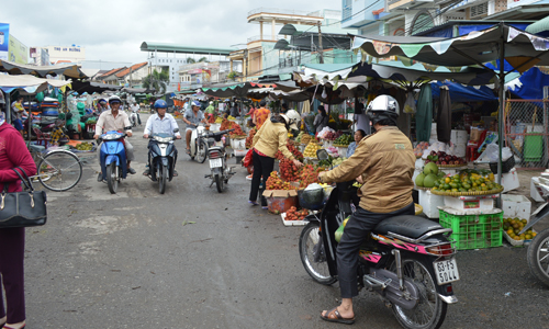 Sạp trái cây dọn chiếm 1/2  con đường bên hông vào chợ.