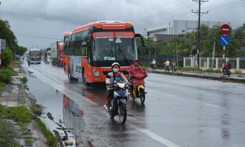 Người điều khiển xe gắn máy phải lấn làn dành cho ô tô vì vũng nước đọng trên QL1.