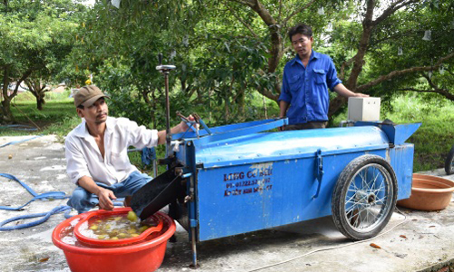 Anh Trần Huỳnh Long (đứng) và thiết bị rửa sa pô do anh sáng chế.