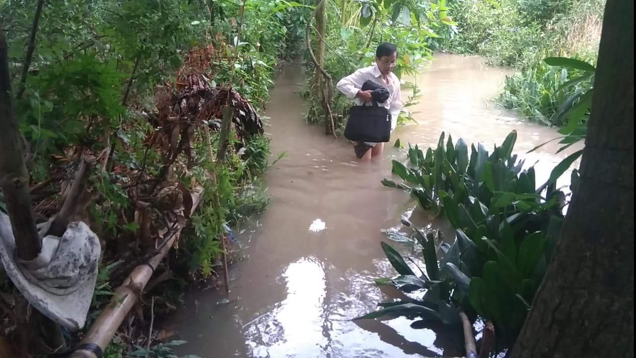 Người dân phải lội qua đoạn đường sạt lở để đi ra đường công cộng.
