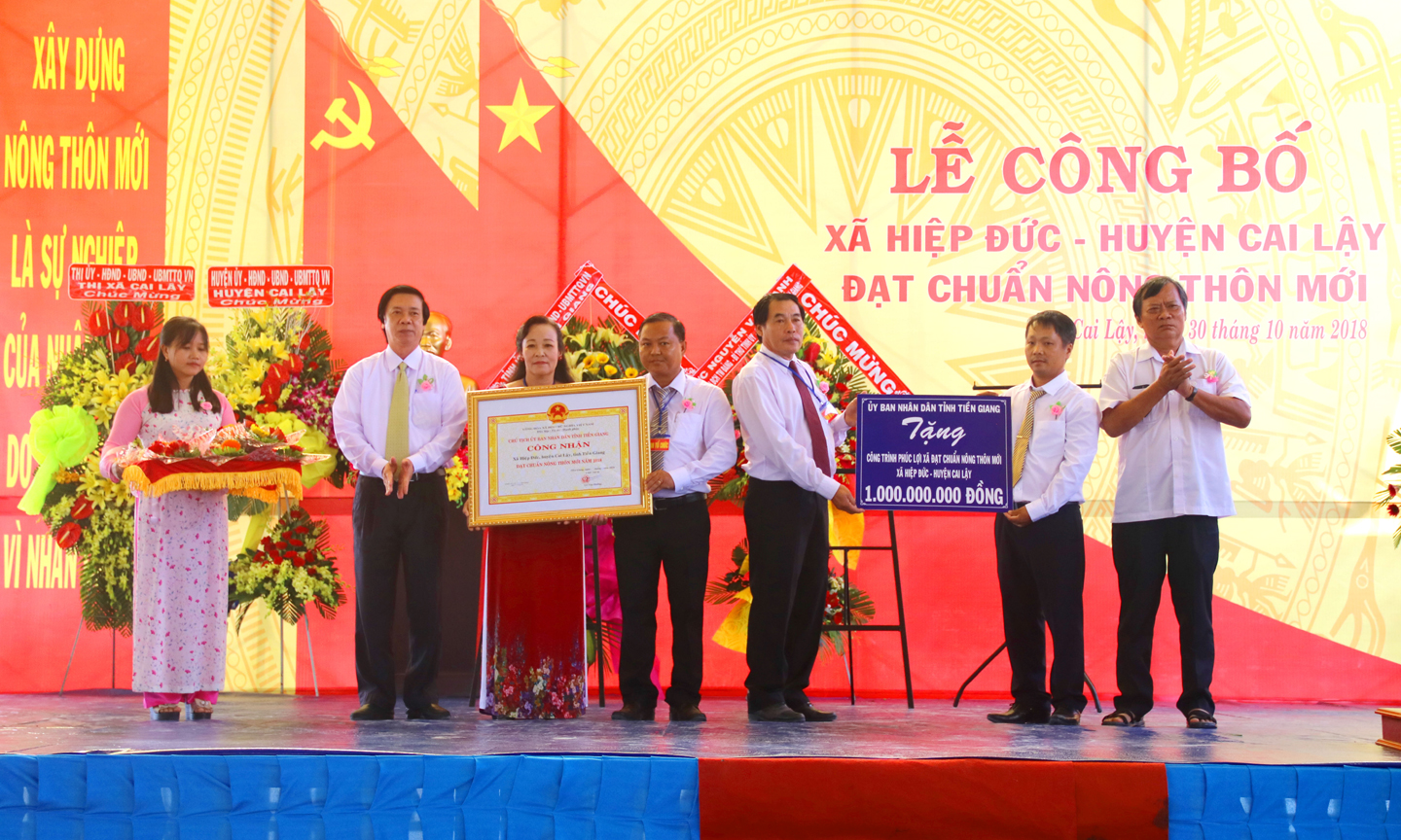 Lãnh đạo tỉnh trao Bằng công nhận đạt chuẩn NTM và Bảng tượng trưng công trình phúc lợi trị giá 1 tỷ đồng cho xã Hiệp Đức.                                                                                                                                     Ảnh: QUỐC TUẤN