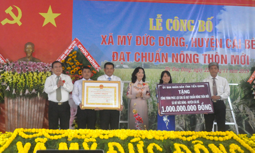  Đồng chí Võ Văn Bình và đồng chí Nguyễn Thị Sáng trao Bằng công nhận và Bảng tượng trưng công trình phúc lợi trị giá 1 tỷ đồng cho xã Mỹ Đức Đông.                                                                                    Ảnh: HỮU CHÍ