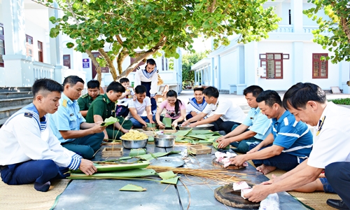 Quân dân Trường Sa quây quần bên nhau gói bánh chưng ngày Tết. Ngoài những lá giông từ đất liền chuyển vào, cán bộ, chiến sĩ ở Trường Sa còn “sáng tạo” dùng lá bàn vuông để gói bánh. Bánh chưng lá bàn vuông có hương vị đặc biệt, là một “chất riêng” của cái Tết nơi đầu sóng ngọn gió.