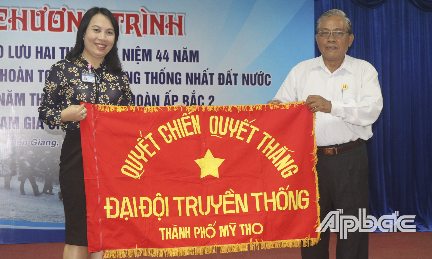 Đại tá Lê Văn Rô trao lại lá cờ truyền thống của Đại đội Trường THPT Nguyễn Đình Chiểu lại cho Đoàn trường.