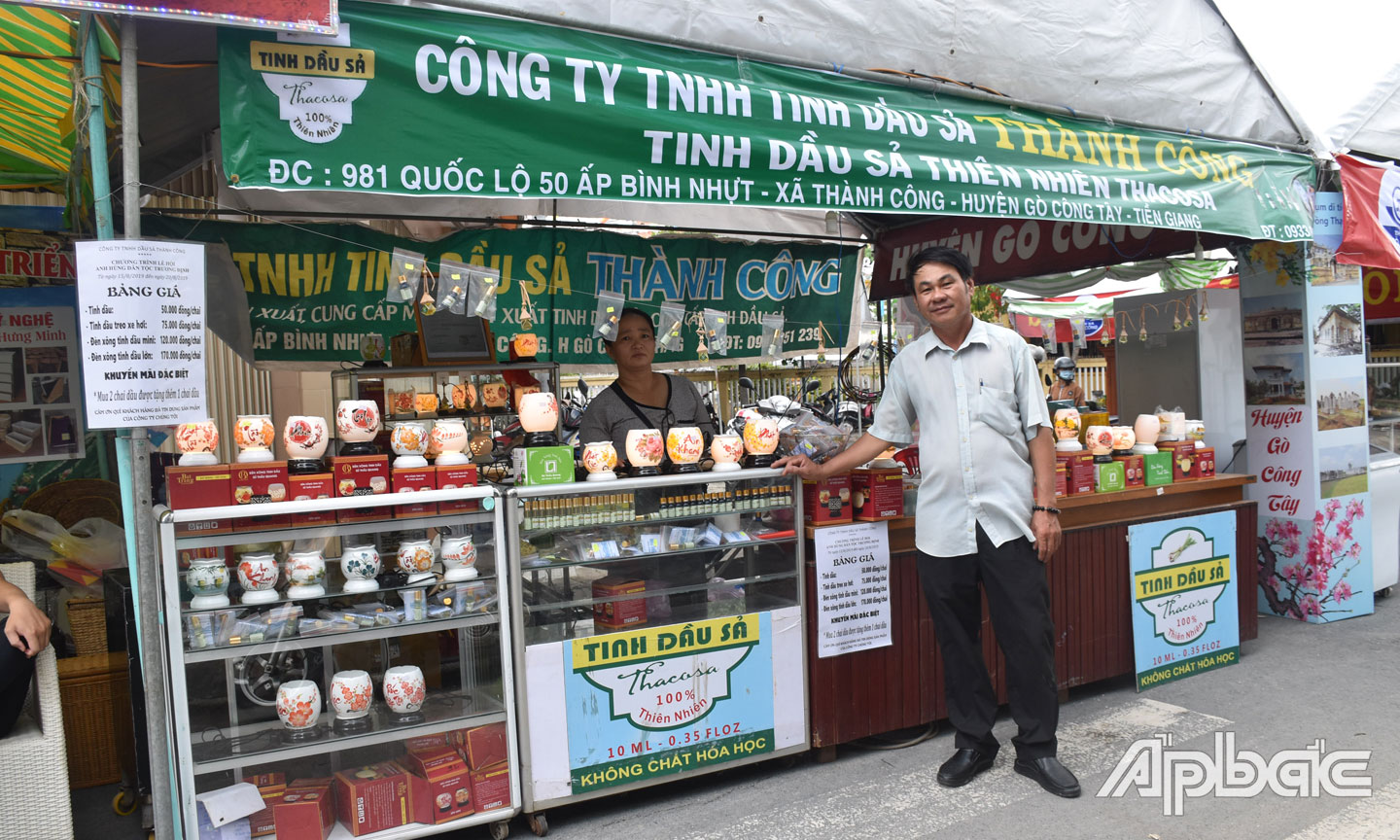 Ông Mừng bên cạnh gian hàng trưng bày, giới thiệu sản phẩm tinh dầu sả.