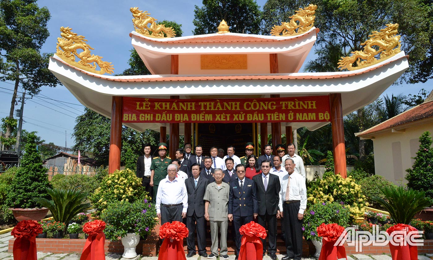 Các đại biểu chụp ảnh lưu niệm tại Bia ghi dấu ấn địa điểm xét xử đầu tiên ở Nam bộ.