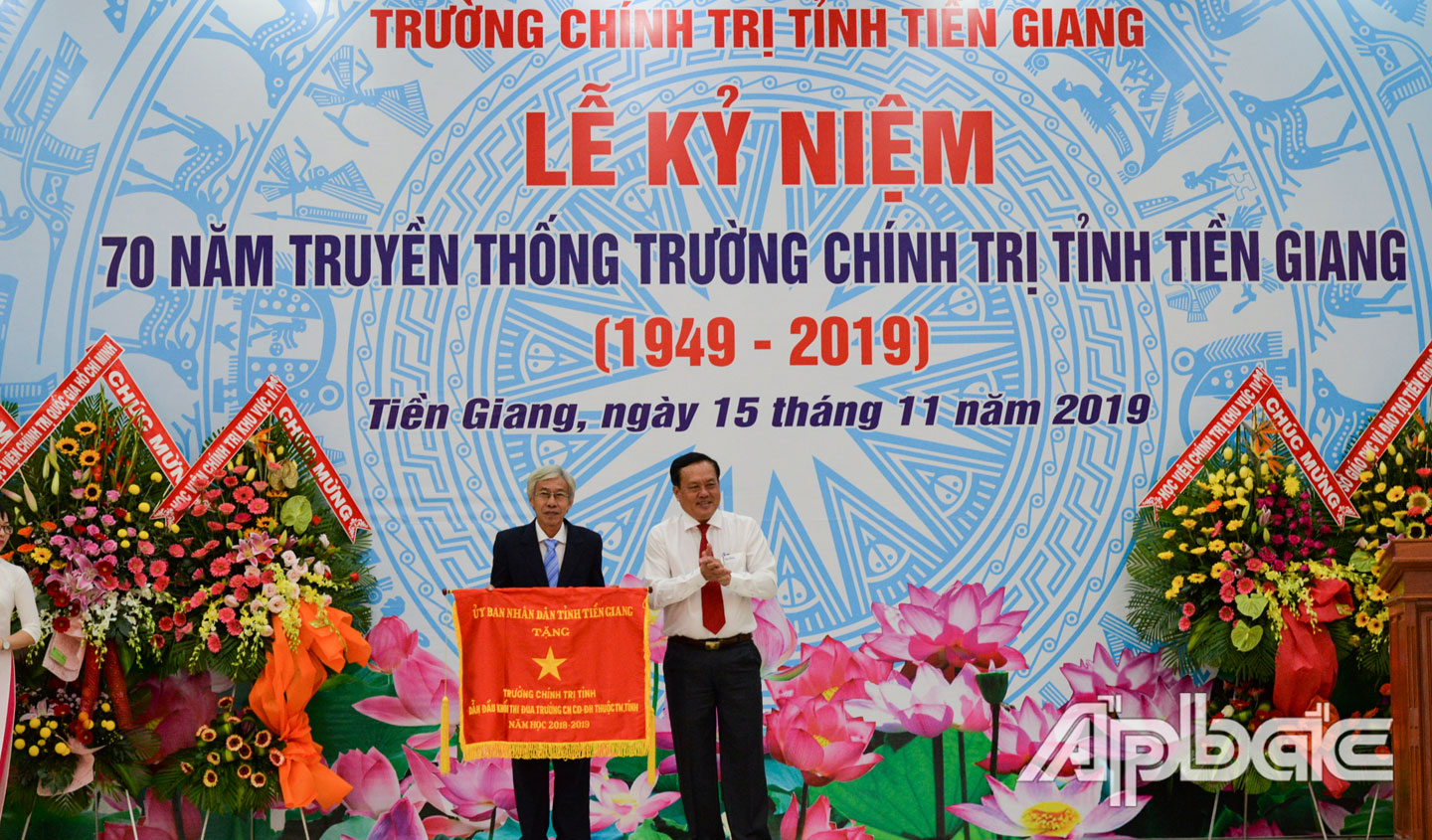 Phó Chủ tịch Thường trực UBND tỉnh Lê Văn Nghĩa trao Cờ thi đua của UBND tỉnh Tiền Giang cho Trường Chính trị. 			              				                                                                                                                               Ảnh: VĂN THẢO