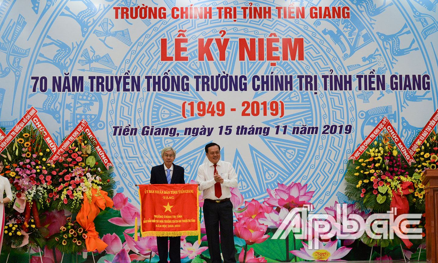 Phó Chủ tịch Thường trực UBND tỉnh Lê Văn Nghĩa trao Cờ thi đua của UBND tỉnh Tiền Giang cho Trường Chính trị. 			              				                                                                                                                               Ảnh: VĂN THẢO
