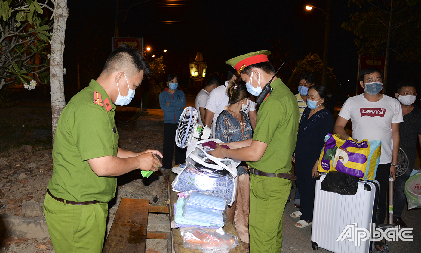 Người thân của công dân đến khu cách ly Trường quân sự Tiền Giang từ rất sớm, mang theo các vật dụng sinh hoạt khác. Lực lượng chức năng đang kiểm tra hành lý trước khi chuyển đến các công dân tham gia cách ly. 