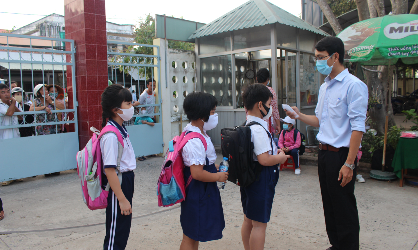 Học sinh xếp hàng ngay ngắn chờ đo thân nhiệt tại Trường Tiểu học Nguyễn Huệ.