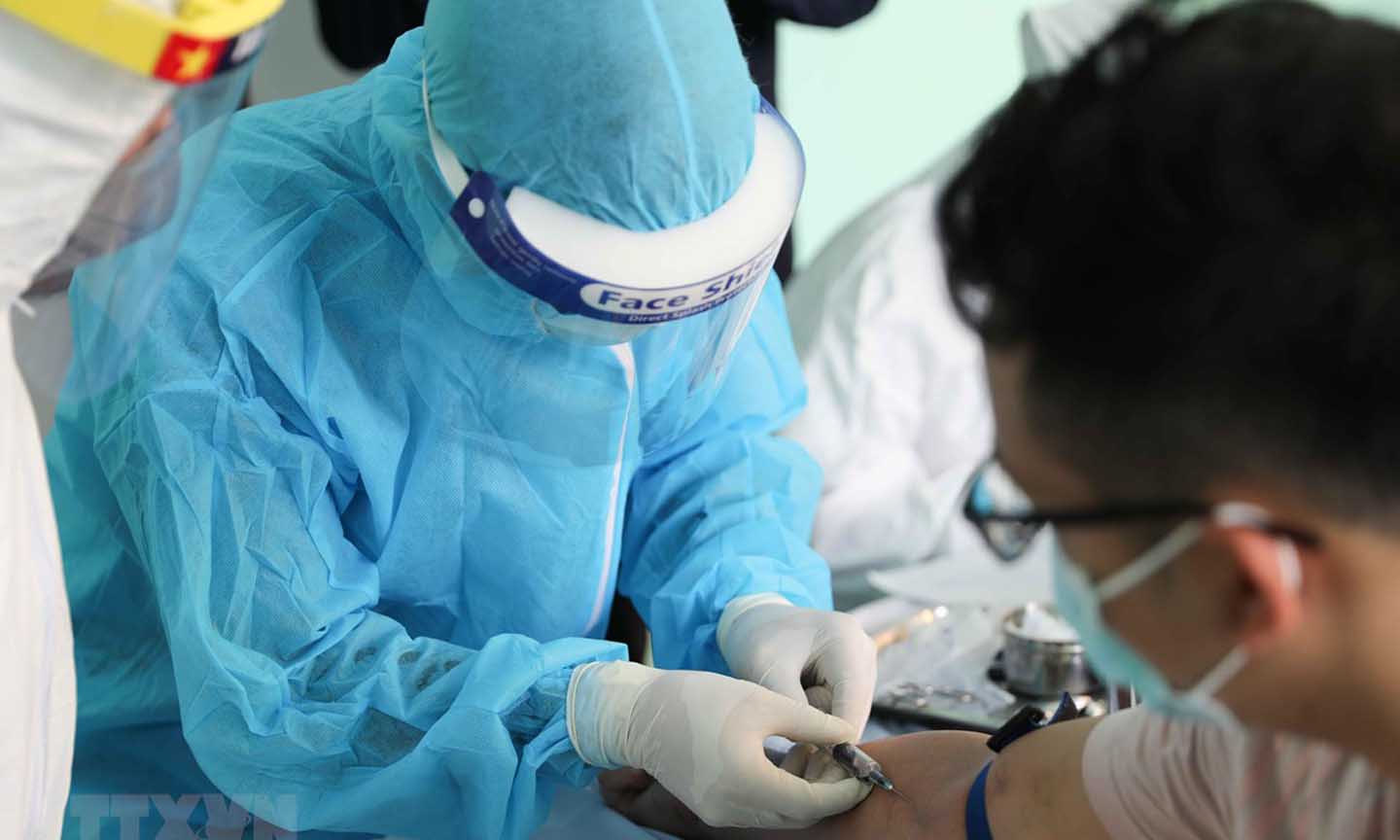 Nhân viên y tế lấy mẫu máu để xét nghiệm nhanh COVID-19 cho người dân. (Ảnh: Thanh Tùng/TTXVN)