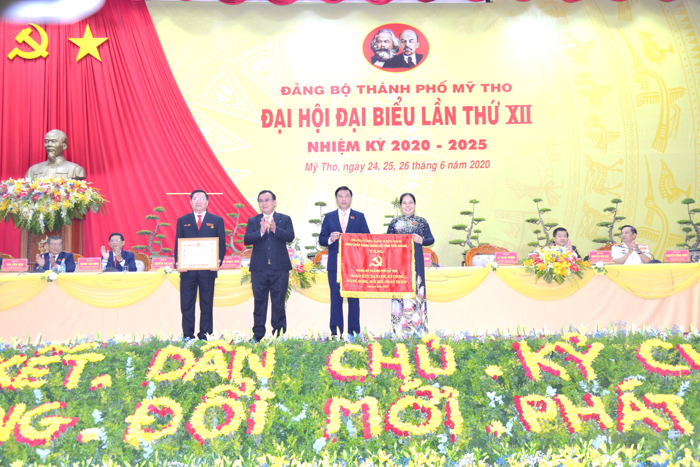 Đồng chí Võ Văn Bình, Phó Bí thư Thường trực Tỉnh ủy, Trưởng đoàn Đại biểu Quốc hội đơn vị tỉnh Tiền Giang trao Bức trướng của Ban Chấp hành Đảng bộ tỉnh Tiền Giang tặng Đảng bộ TP. Mỹ Tho với dòng chữ “Đảng bộ thành phố Mỹ Tho Đoàn kết - Dân chủ - Kỹ cương - Năng động - Đổi mới - Phát triển”.
