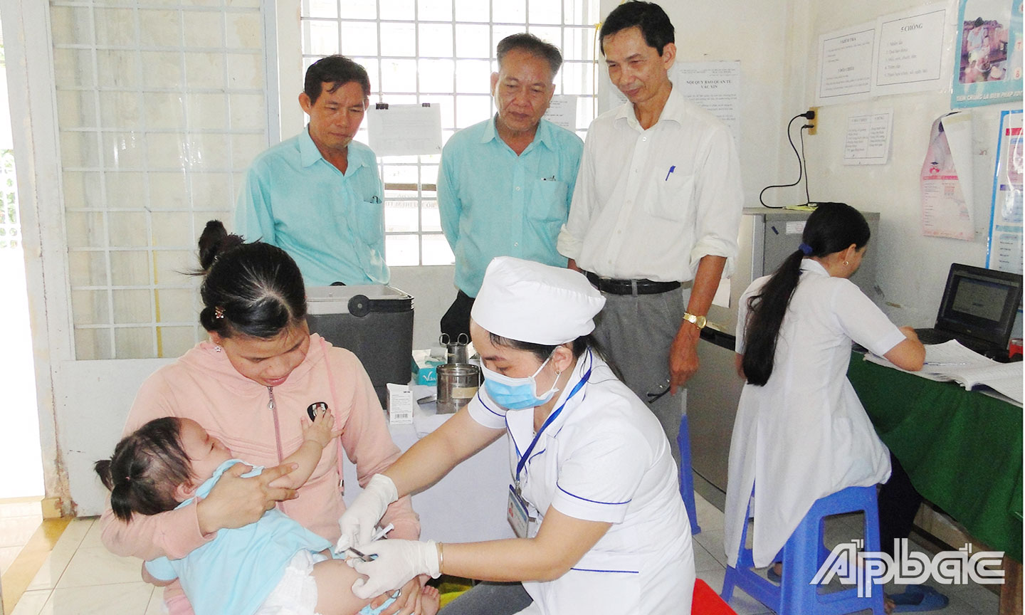 Bác sĩ CKII Lê Đăng Ngạn (bên phải) giám sát tiêm chủng an toàn cho trẻ em.