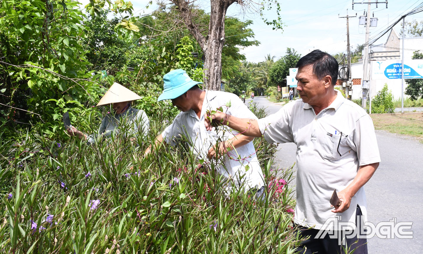 Đồng chí Huỳnh Văn Mười tham gia làm đẹp đường hoa trong ấp.