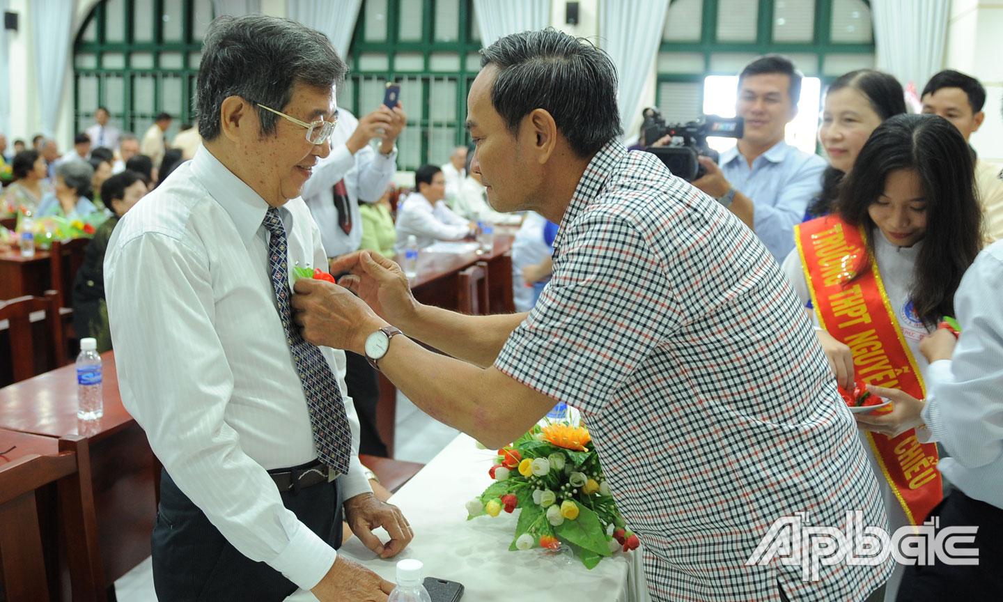 Nguyên Thứ trưởng Bộ Tài chính Nguyễn Hữu Chí, cựu học sinh nhà trường cài hoa tri ân cho Thầy Lê Ngọc Trấn, nguyên Hiệu Trường THPT Nguyễn Đình Chiểu.