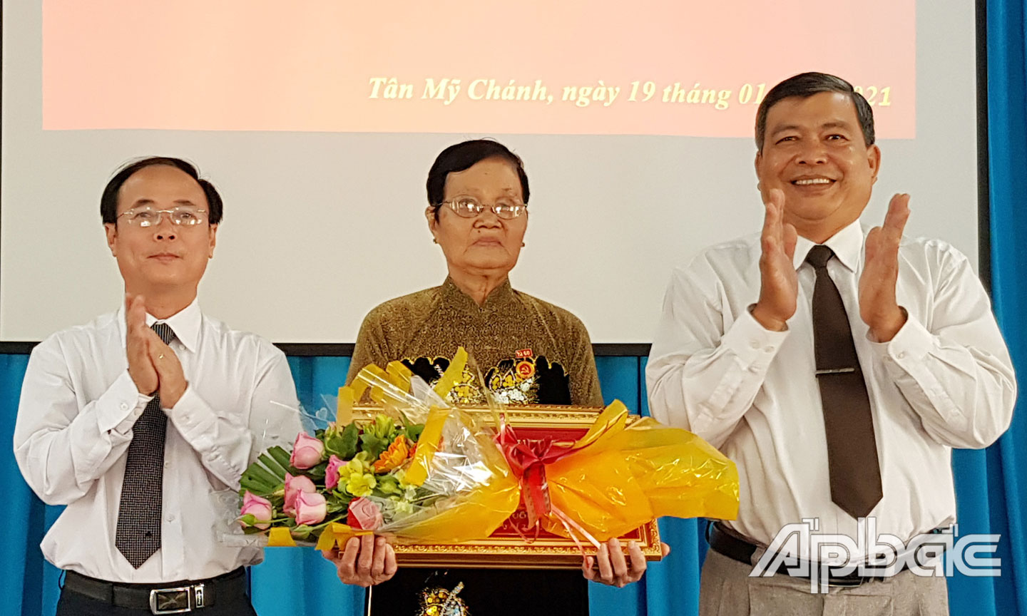 Đồng chí Trần Kim Trát (bìa trái) và đồng chí Bùi Văn Bảo, Trưởng Ban Dân vận Thành ủy Mỹ Tho, Chủ tịch Ủy ban MTTQ TP. Mỹ Tho trao tặng Huy hiệu 60 năm tuổi Đảng và quà chúc mừng đảng viên Lê Thị Hồng Thắng.
