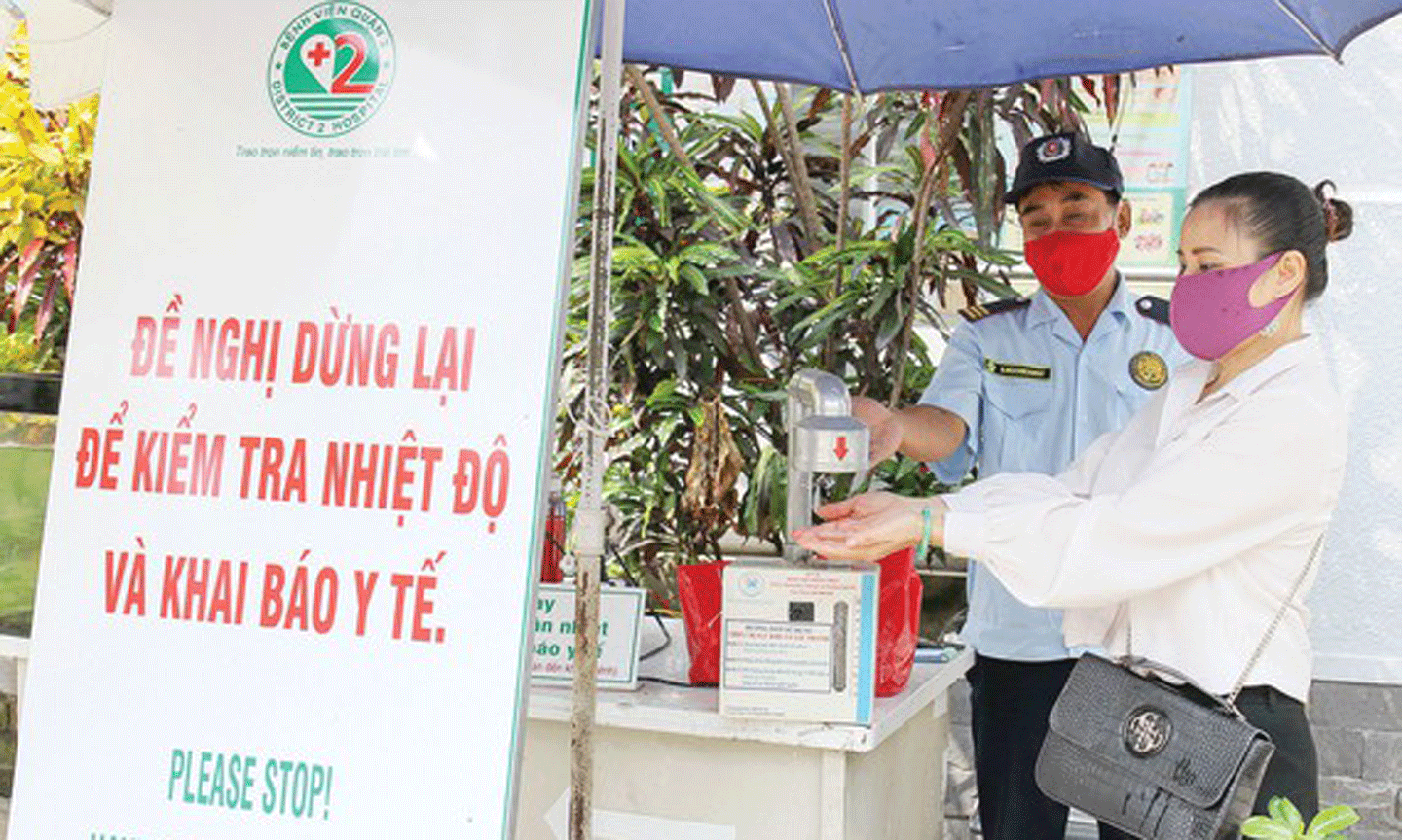 Nhân viên bảo vệ Trung tâm Y tế Thảo Điền, quận 2, TPHCM hướng dẫn người dân sát khuẩn trước khi vào trung tâm. Ảnh: HOÀNG HÙNG