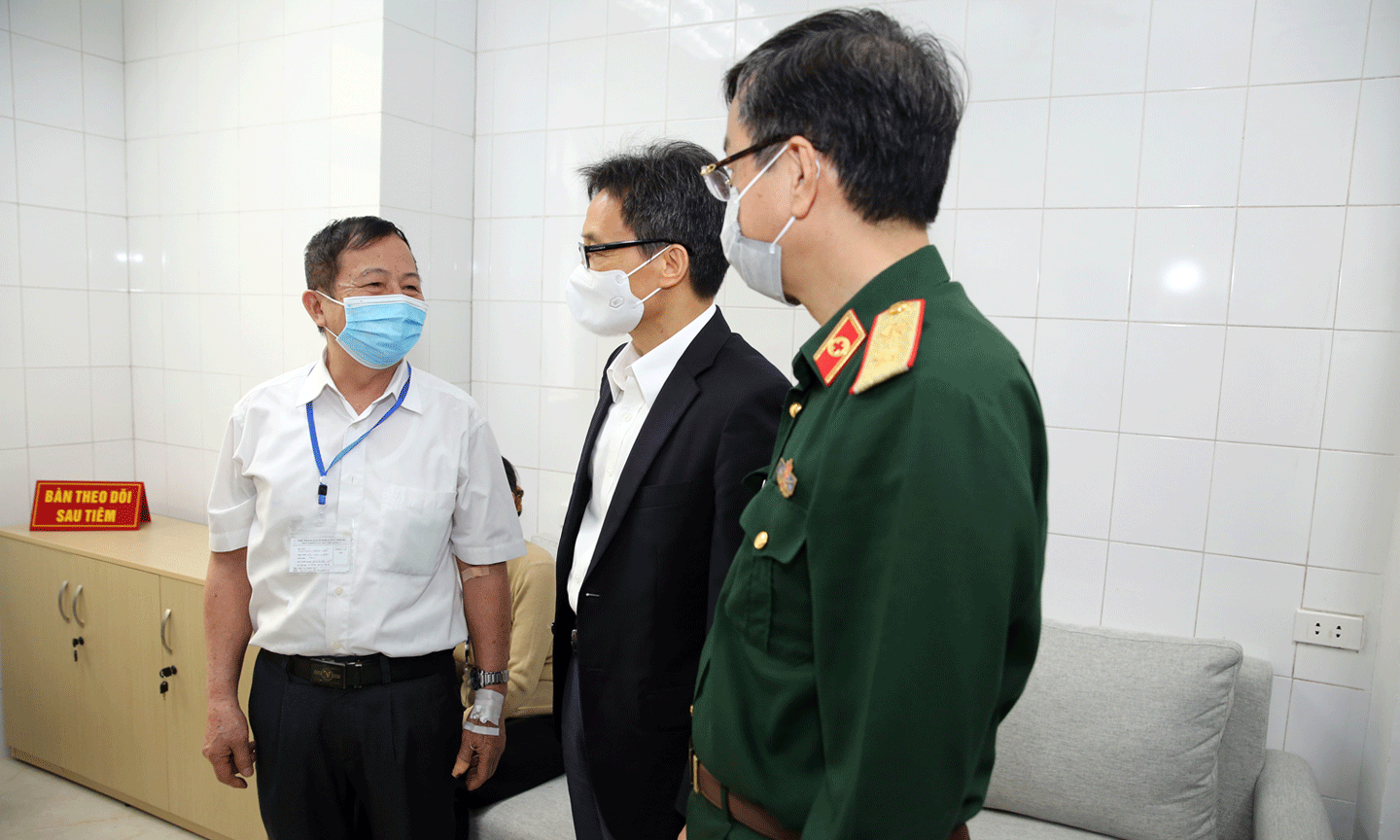 Phó Thủ tướng Vũ Đức Đam trò chuyện với một tình nguyện viên cao tuổi đang theo dõi sau tiêm. Ảnh: VGP/Đình Nam 