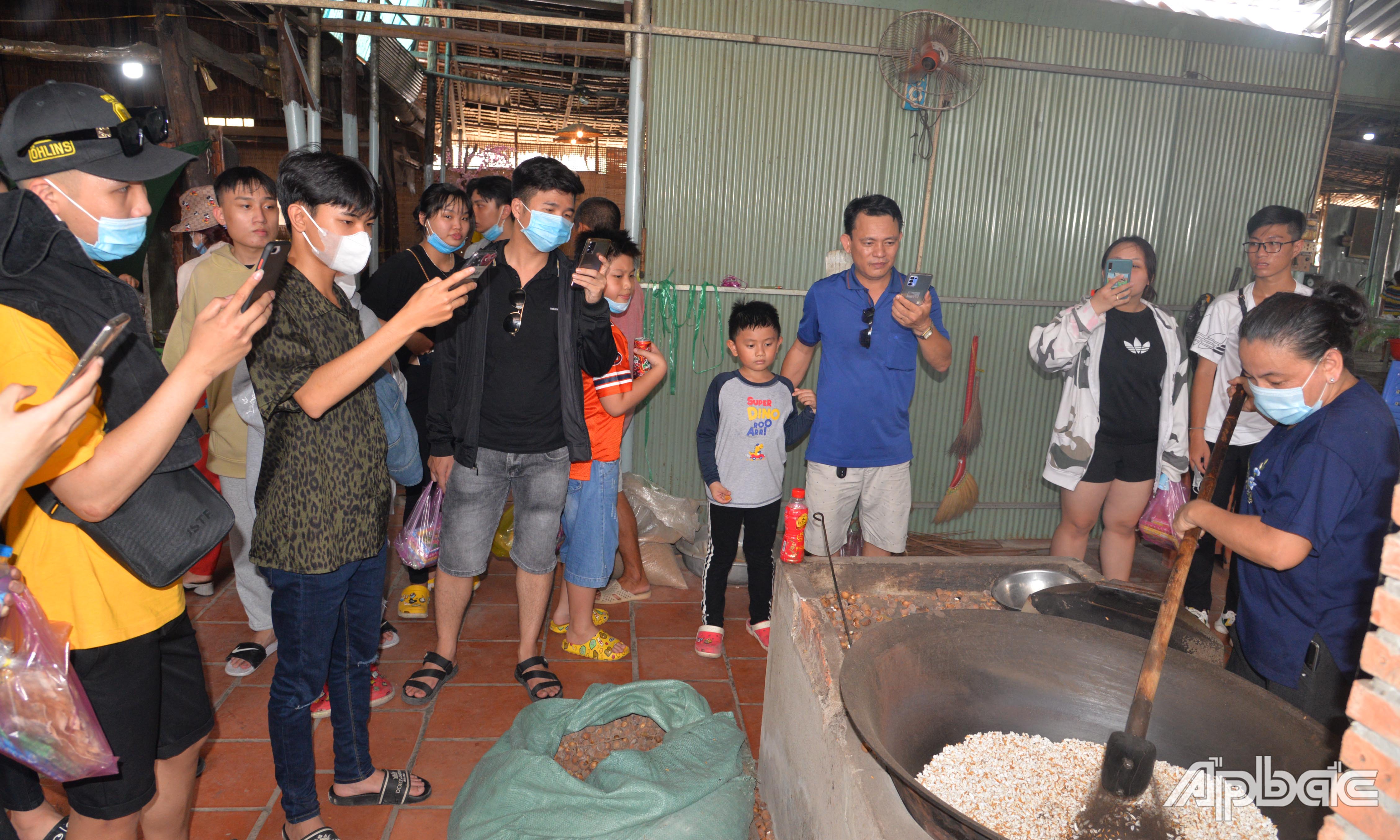 Khách tham quan trải nghiệm quy trình làm cốm ở Làng nghề cốm An Ninh.